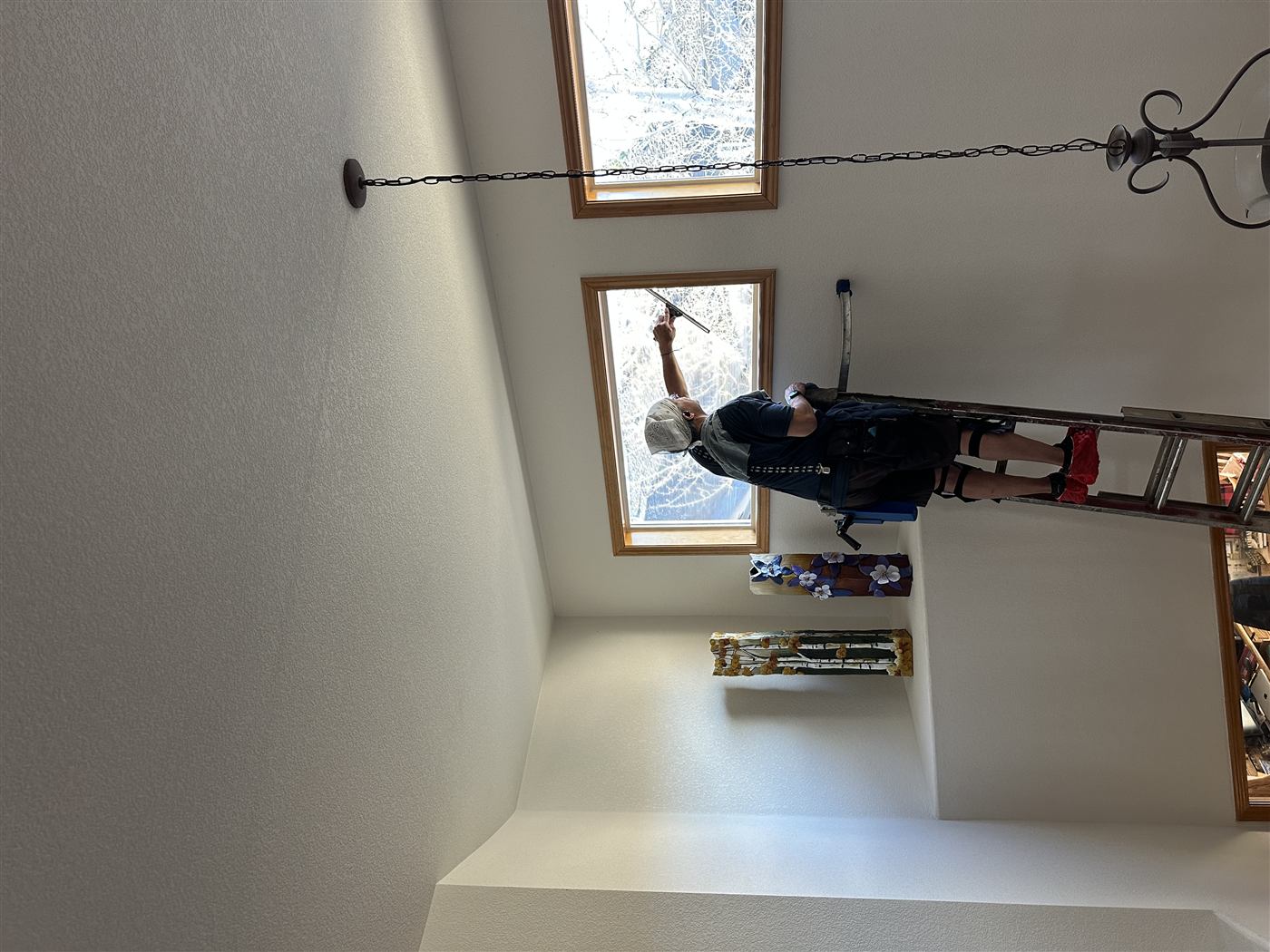 Cleaning elevated windows from an interior ladder.